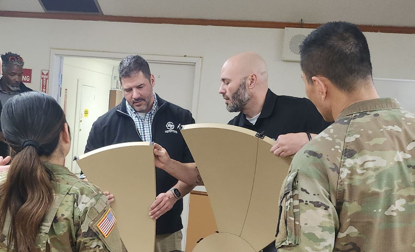 Two employees instructing with an antenna and two military personnel watching