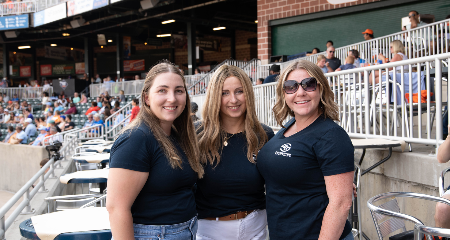 employees smiling at a corporate event in a baseball stadium