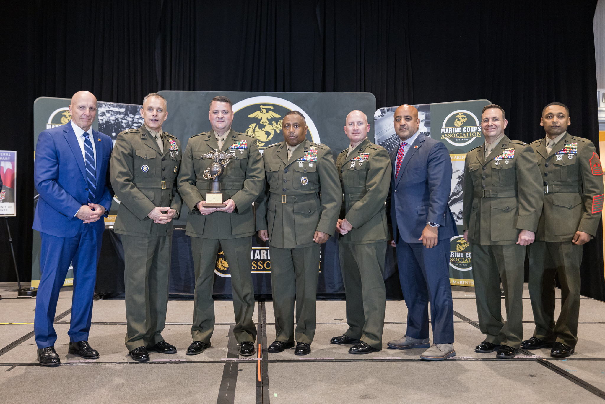 CEO Edwin "Eddie" Peña posing on a stage with group of Marines during award ceremony